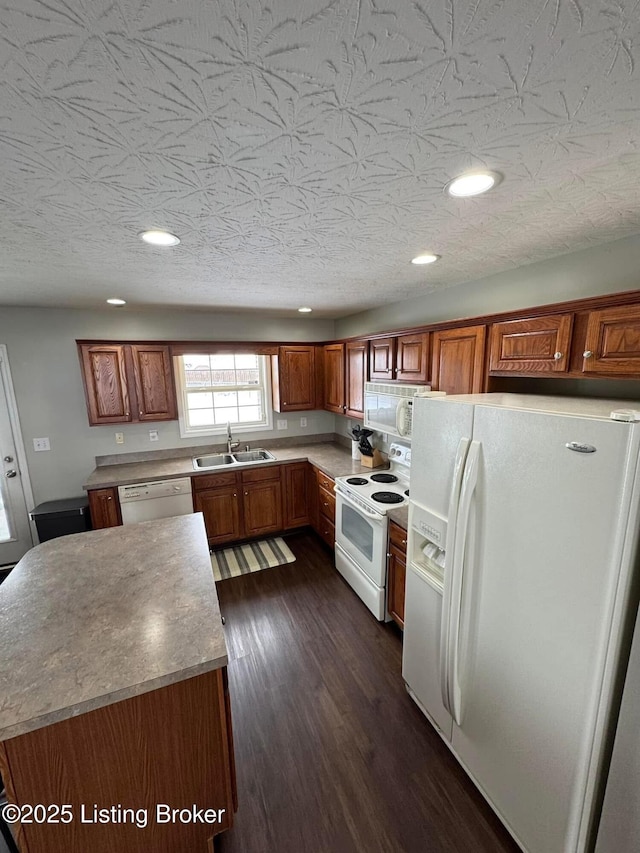 kitchen with a textured ceiling, dark hardwood / wood-style flooring, white appliances, and sink