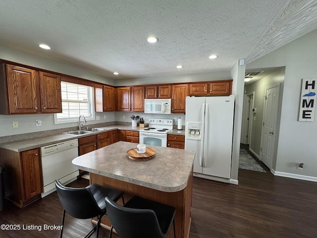 kitchen featuring dark hardwood / wood-style flooring, a textured ceiling, white appliances, sink, and a center island