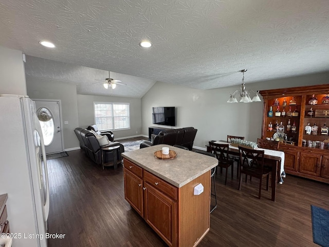 kitchen with a center island, lofted ceiling, white refrigerator, a textured ceiling, and decorative light fixtures