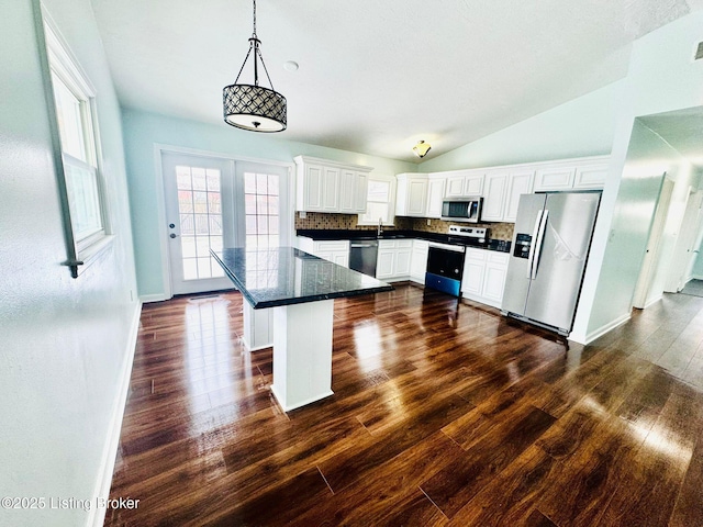 kitchen with backsplash, pendant lighting, white cabinetry, appliances with stainless steel finishes, and a breakfast bar area