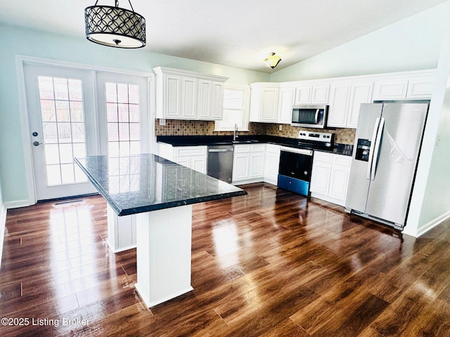 kitchen with stainless steel appliances, tasteful backsplash, lofted ceiling, hanging light fixtures, and white cabinets