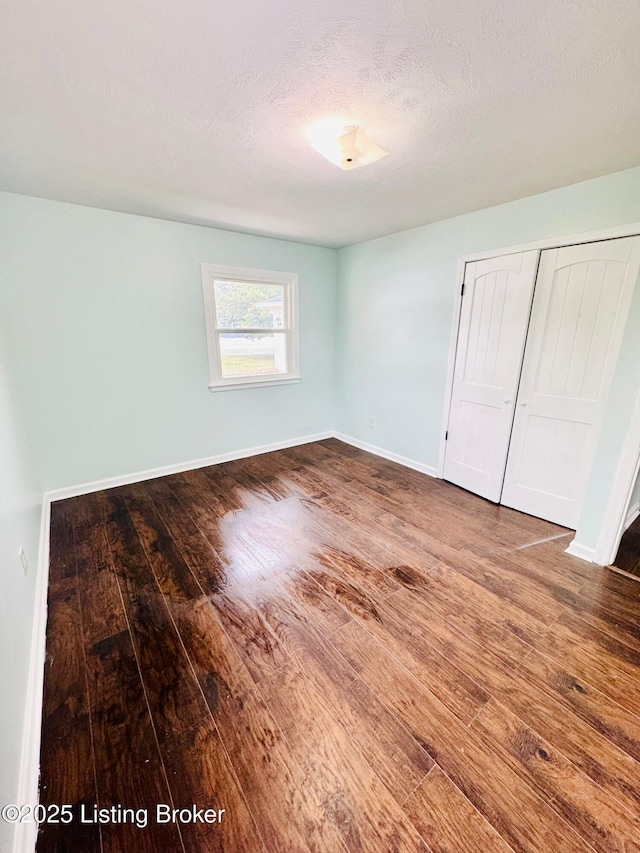 unfurnished bedroom with a textured ceiling, a closet, and hardwood / wood-style floors