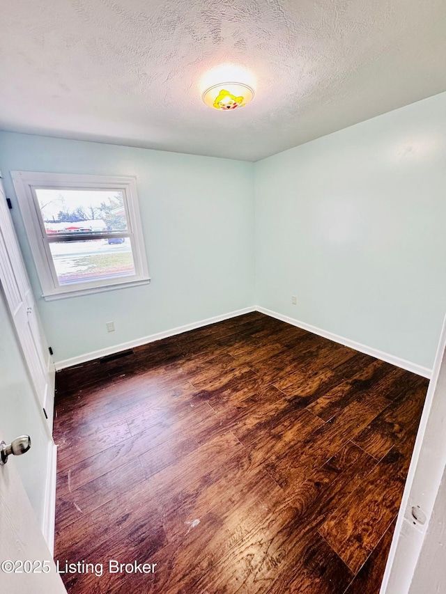 empty room featuring dark wood-type flooring and a textured ceiling