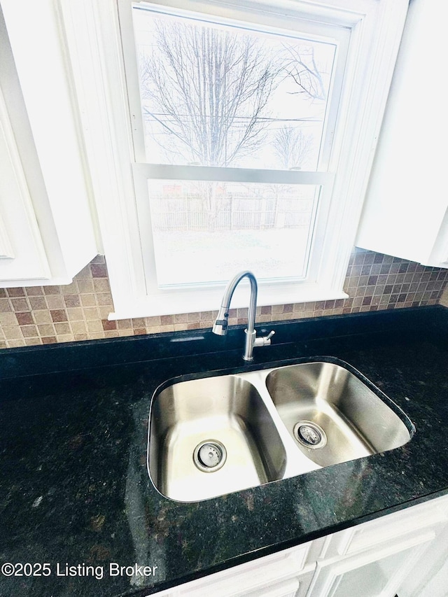 room details with decorative backsplash, white cabinets, and sink