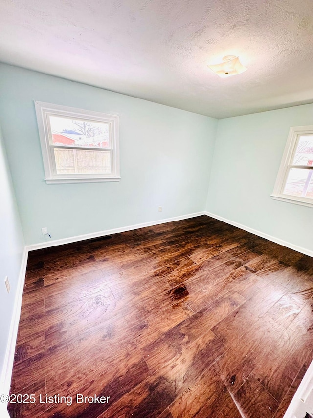 empty room featuring a textured ceiling and dark wood-type flooring