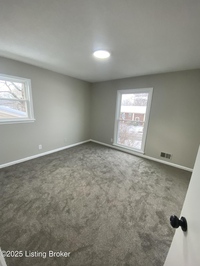 spare room with dark carpet and a healthy amount of sunlight