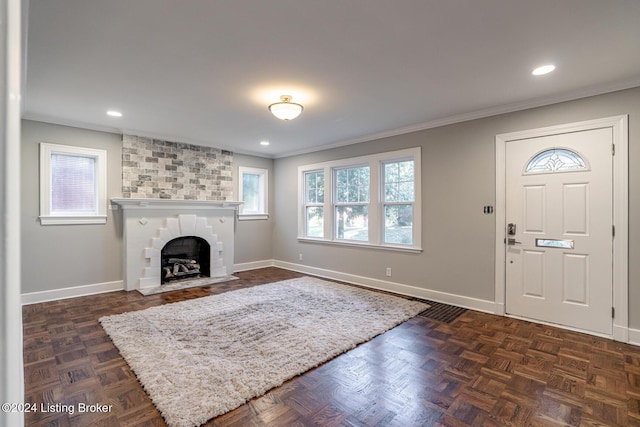 foyer featuring dark parquet flooring, ornamental molding, and a fireplace