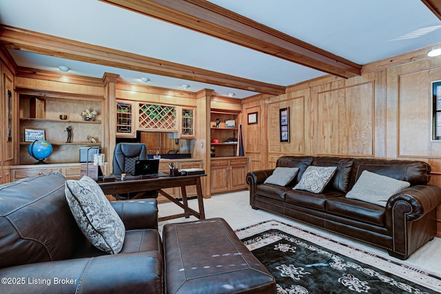 carpeted living room with beamed ceiling, wood walls, and built in shelves