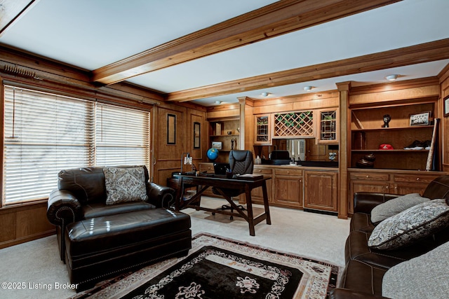 office space featuring beamed ceiling, ornamental molding, light carpet, wood walls, and bar area