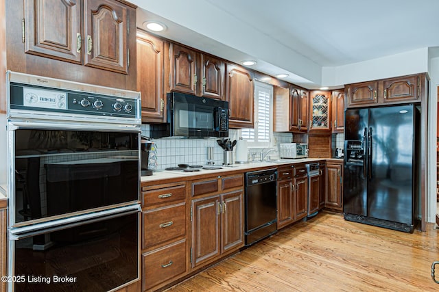 kitchen featuring light hardwood / wood-style flooring, black appliances, and decorative backsplash