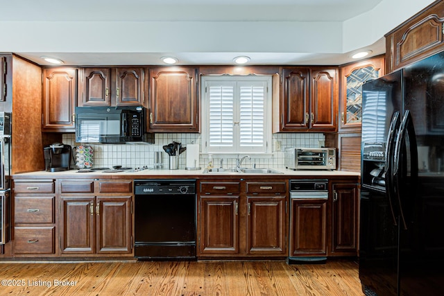 kitchen with backsplash, light hardwood / wood-style flooring, black appliances, and sink