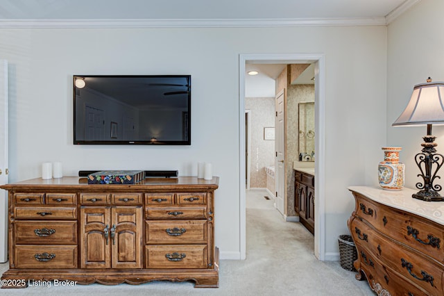 carpeted bedroom featuring ensuite bath and crown molding