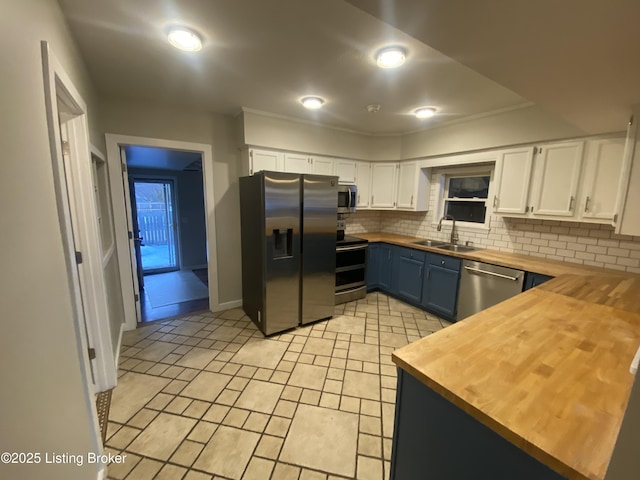 kitchen with butcher block counters, white cabinetry, sink, stainless steel appliances, and blue cabinets