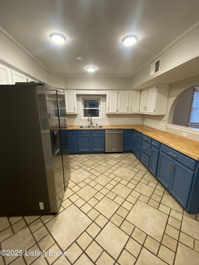 kitchen with blue cabinetry, white cabinetry, sink, appliances with stainless steel finishes, and ornamental molding