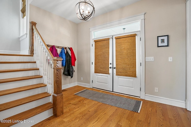 foyer entrance with an inviting chandelier, light hardwood / wood-style floors, and french doors