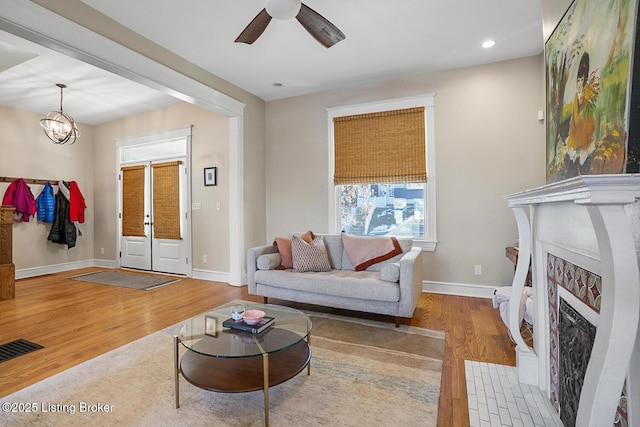 living room featuring ceiling fan with notable chandelier and light wood-type flooring