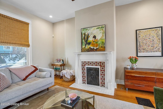 living room featuring a tiled fireplace and hardwood / wood-style floors