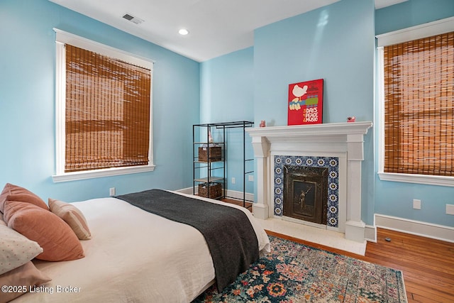 bedroom with hardwood / wood-style floors and a high end fireplace