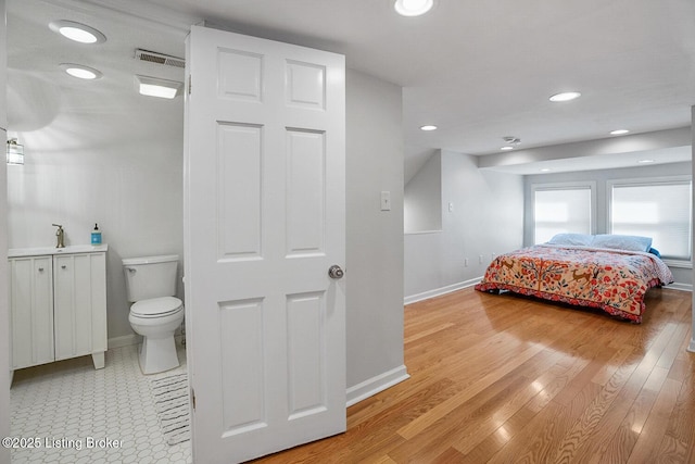 bedroom with ensuite bath, sink, and light wood-type flooring