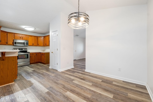 kitchen featuring a notable chandelier, decorative light fixtures, light wood-type flooring, and stainless steel appliances