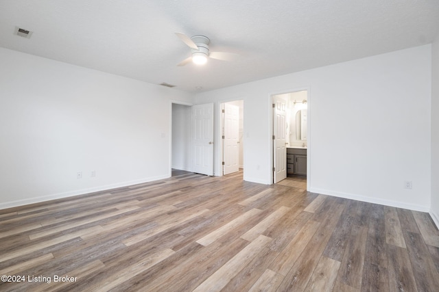 unfurnished bedroom with light wood-type flooring, a textured ceiling, connected bathroom, and ceiling fan