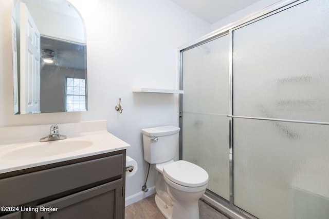 bathroom featuring vanity, hardwood / wood-style flooring, toilet, and a shower with door