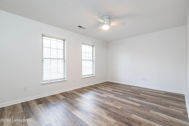 empty room with hardwood / wood-style flooring, ceiling fan, and a textured ceiling