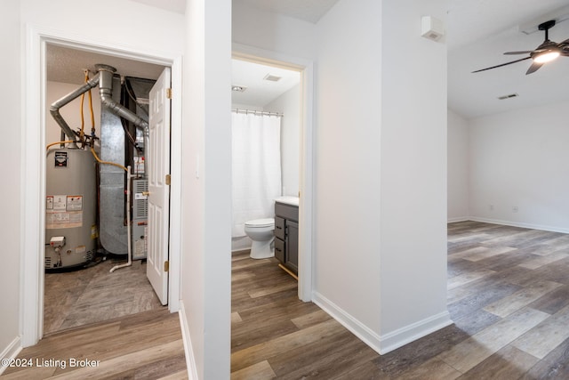 hall with light hardwood / wood-style floors, heating unit, and water heater