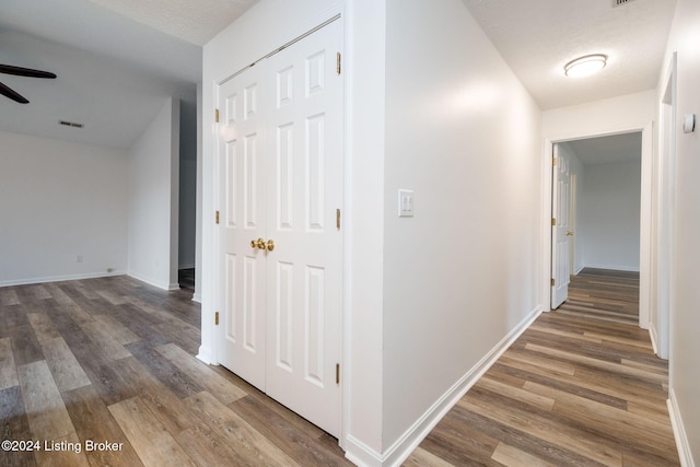 corridor with dark hardwood / wood-style flooring and a textured ceiling