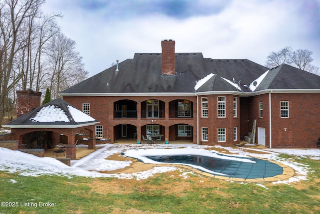 snow covered property with a patio, a covered pool, and a yard