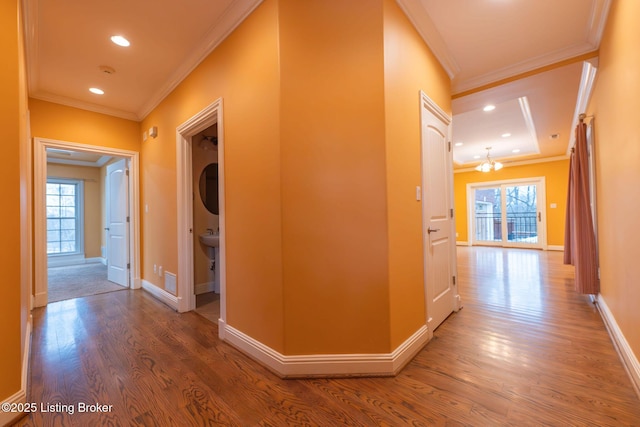 corridor with hardwood / wood-style floors, crown molding, and plenty of natural light