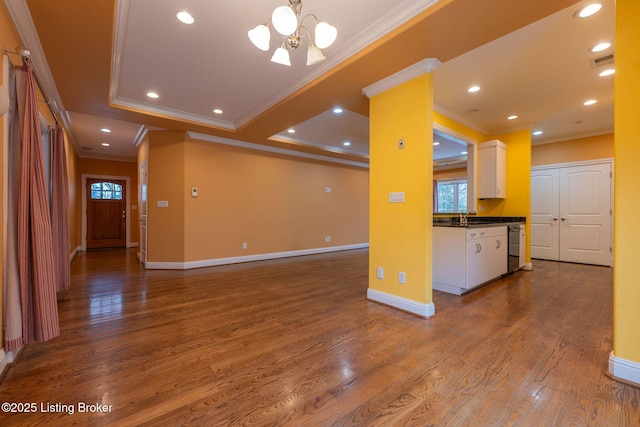 unfurnished living room with an inviting chandelier, hardwood / wood-style floors, and ornamental molding