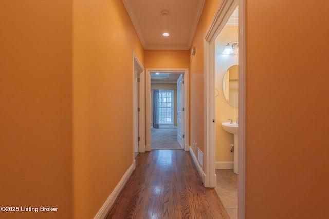 hall with ornamental molding and wood-type flooring