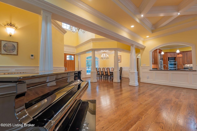 misc room with an inviting chandelier, beam ceiling, decorative columns, coffered ceiling, and light wood-type flooring