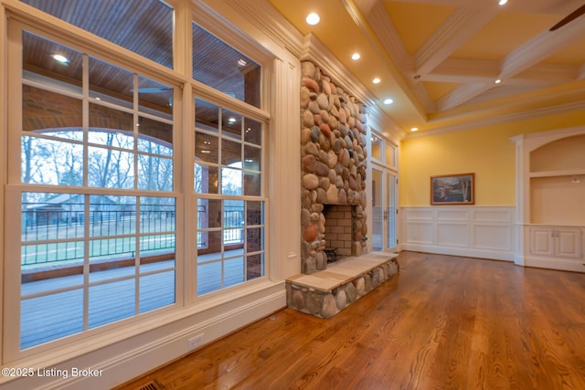 unfurnished living room with a fireplace, wood-type flooring, coffered ceiling, crown molding, and beam ceiling