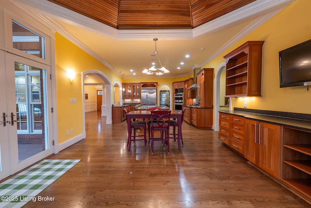 dining space featuring a high ceiling, crown molding, dark wood-type flooring, and an inviting chandelier