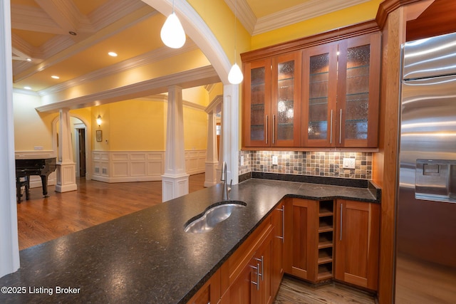 bar featuring sink, dark hardwood / wood-style flooring, stainless steel fridge with ice dispenser, decorative light fixtures, and ornate columns