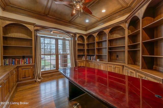 unfurnished office featuring hardwood / wood-style floors, built in features, ornamental molding, coffered ceiling, and ceiling fan