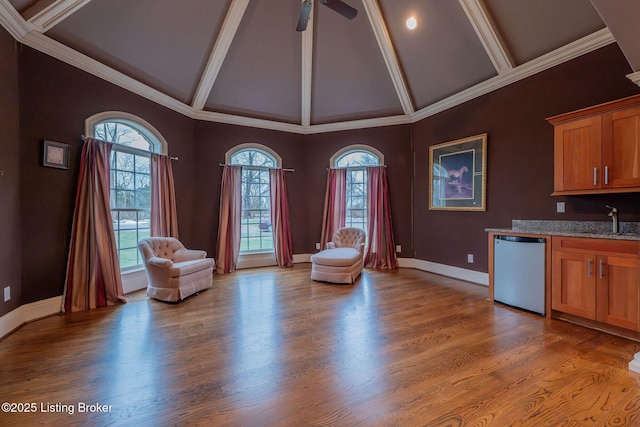 unfurnished room with high vaulted ceiling, indoor wet bar, beamed ceiling, ceiling fan, and hardwood / wood-style floors