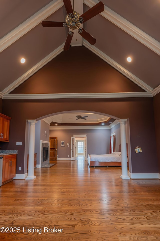 unfurnished living room featuring wood-type flooring, ornamental molding, ceiling fan, and ornate columns