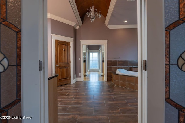 corridor with lofted ceiling, ornamental molding, and a notable chandelier