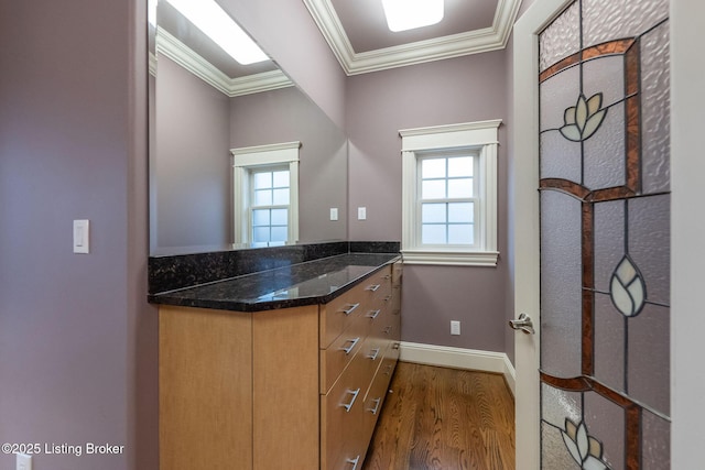 interior space featuring a healthy amount of sunlight, ornamental molding, hardwood / wood-style floors, and vanity