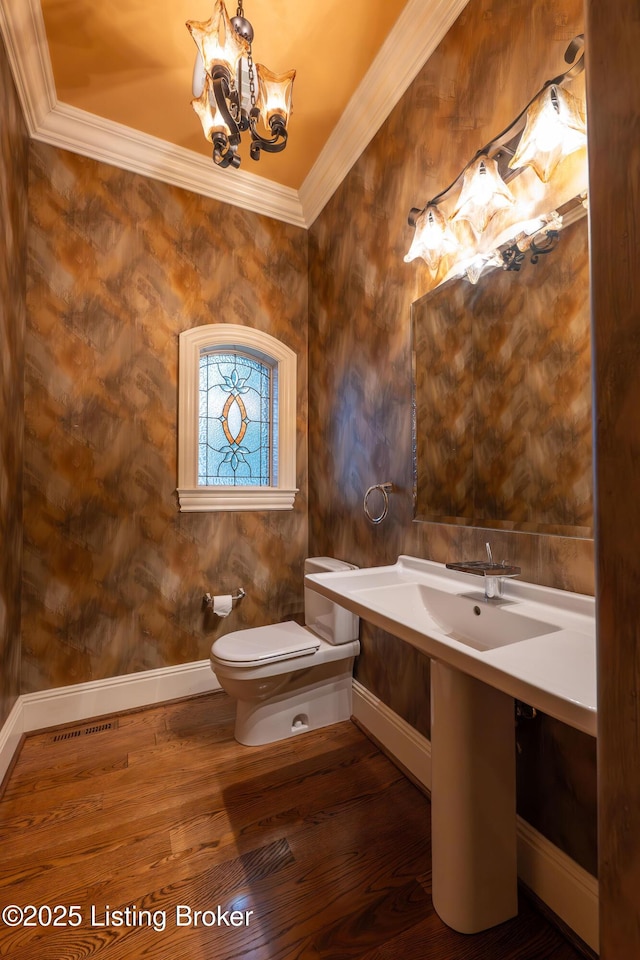 bathroom featuring ornamental molding, toilet, a chandelier, and wood-type flooring