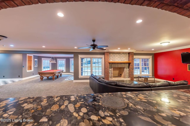 unfurnished living room featuring crown molding, billiards, ceiling fan, a fireplace, and carpet floors