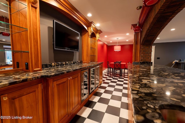 bar featuring decorative columns, crown molding, dark stone countertops, and pendant lighting