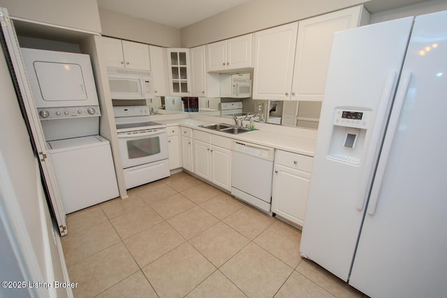 kitchen featuring white appliances, white cabinetry, stacked washer / dryer, and sink