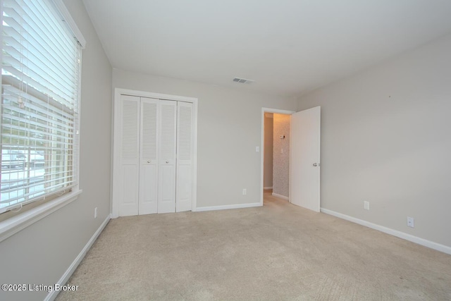 unfurnished bedroom featuring light colored carpet, multiple windows, and a closet