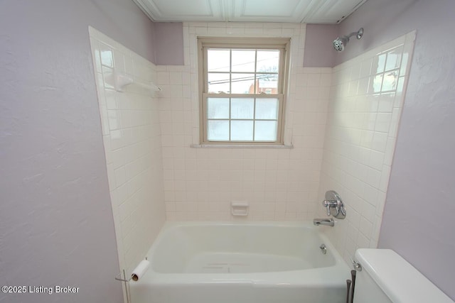 bathroom featuring tiled shower / bath combo and toilet