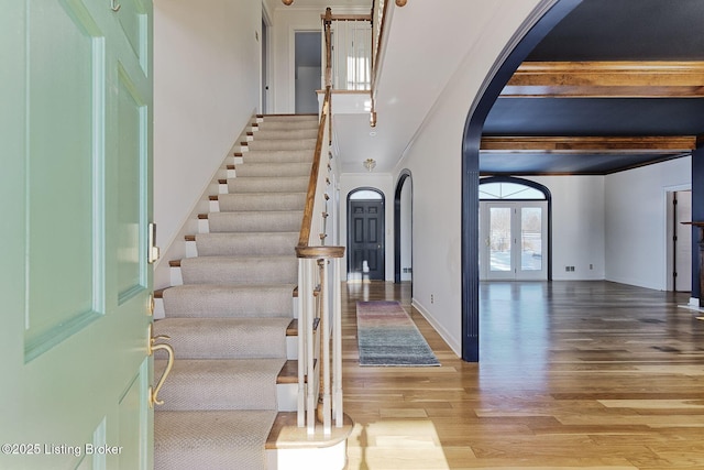 staircase featuring beam ceiling and hardwood / wood-style floors