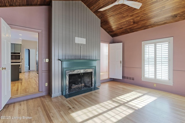 unfurnished living room with ceiling fan, light hardwood / wood-style floors, a premium fireplace, high vaulted ceiling, and wood ceiling